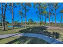 Scenic golf course view with mature trees, a tranquil pond, and a walking path on a sunny day at 8005 Bardmoor Pl # 202I, Seminole, FL 33777