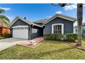 Charming single-story home featuring an attached two-car garage, a front bench, and manicured lawn at 10322 Goldenbrook Way, Tampa, FL 33647