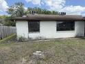 Exterior view of a single-story home showing the yard and boarded up windows at 12812 1St Isle, Hudson, FL 34667