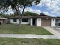 Modest single-story home with a brown roof, a front yard, and an attached one car garage at 12812 1St Isle, Hudson, FL 34667