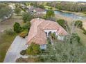 An aerial view of this gorgeous home featuring a beautiful tile roof, landscaping, and access to a community lake at 13315 Carnoustie Cir, Dade City, FL 33525