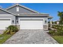 A home's three-car garage with brick pavers, stone accents, and manicured landscaping providing an inviting curb appeal at 18491 Green Garden Ct, Venice, FL 34293