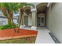 Inviting front entrance with landscaped beds, covered archway, and tiled walkway leading to the front door at 5809 War Admiral Dr, Wesley Chapel, FL 33544