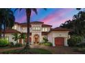 Elegant two-story home featuring a red tile roof, manicured landscaping, and a spacious driveway at 1097 Eden Isle Ne Dr, St Petersburg, FL 33704