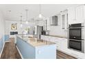 Bright kitchen with a large island, white cabinets, modern appliances, and tiled backsplash at 210 Lee St, Oldsmar, FL 34677