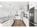 Modern kitchen with white cabinets, stainless steel appliances, granite counters, and wood-style flooring at 210 Lee St, Oldsmar, FL 34677