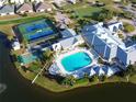 Aerial view showcases a community pool, tennis courts, and clubhouse surrounded by lush landscaping and a lake at 24156 Buckingham Way, Punta Gorda, FL 33980