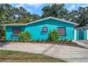 Charming, bright blue one-story home with beautiful landscaping, decorative window boxes, and a concrete driveway at 717 Carolina Ave, Tarpon Springs, FL 34689