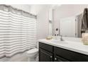 Clean bathroom with striped shower curtain, black vanity with white countertop, and modern fixtures at 7602 S Desoto St, Tampa, FL 33616