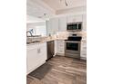 Modern kitchen featuring stainless steel appliances, white cabinetry, and wood-look flooring at 16330 Gulf Blvd # 306, Redington Beach, FL 33708