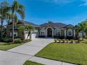 Charming exterior view of this home with a lush front lawn, arched windows, and a two-car garage at 1111 Carriage Park Dr, Valrico, FL 33594