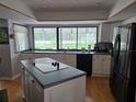 Bright kitchen features an island with cooktop, a large picture window, and stainless steel appliances at 1735 Tall Pine Cir, Safety Harbor, FL 34695