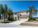 Charming two-story home with a well-manicured lawn, palm trees, and attached two-car garage at 18311 Arbor Crest Dr, Hudson, FL 34667