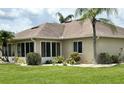 View of the rear exterior showcasing an enclosed porch, well maintained lawn, and lush landscaping at 1311 Caloosa Lake Ct, Sun City Center, FL 33573