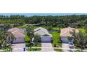 Aerial view of a single-story home with lush landscaping, a brick driveway, and a two-car garage at 15856 Cobble Mill Dr, Wimauma, FL 33598