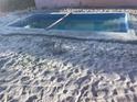 In-ground pool with a bright blue interior surrounded by sand at 6923 Dartmouth N Ave, St Petersburg, FL 33710