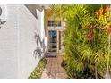 Well-lit front door with glass window and tile flooring surrounded by lush greenery at 4251 Whittner Dr, Land O Lakes, FL 34639