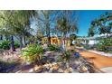 Charming home with a vibrant yellow exterior, surrounded by lush landscaping and trees at 830 S Davis Blvd, Tampa, FL 33606
