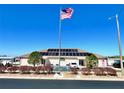 Community center exterior with flagpole and solar panels on roof at Grand Horizons community at 37544 Corey Lewis Ave, Zephyrhills, FL 33541