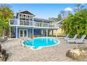 Backyard with a pool surrounded by lounge chairs, trees, and a two-story home with a deck above at 906 W Henry Ave, Tampa, FL 33604
