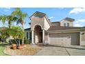Inviting home featuring a two-car garage, well-maintained landscaping, and a stately arched entrance at 4110 Huntingdale Ct, Wesley Chapel, FL 33543