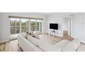 Bright living room with light wood floors, a large comfortable sofa, and sliding glass doors to a balcony at 960 Starkey Rd # 10301, Largo, FL 33771