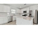 Modern kitchen with stainless steel appliances, white cabinets, and a large island at 1165 Kistna Dr, Zephyrhills, FL 33540