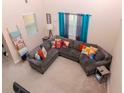 Open-concept living room with sectional sofa, throw pillows, and natural light streaming through large windows at 25925 Terrawood Loop, Land O Lakes, FL 34639