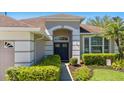 Stylish entryway with a modern front door, manicured hedges, and a well-maintained walkway at 1327 Yardley Dr, Wesley Chapel, FL 33544