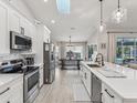 Open concept kitchen with white cabinets, stainless steel appliances, a center island and view of the dining area and pool at 2781 Jarvis Cir, Palm Harbor, FL 34683