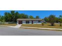 Well maintained single-story home with a brown roof and a green lawn on a sunny day at 5729 13Th St, Zephyrhills, FL 33542