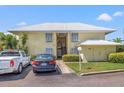 Light yellow condo with a white metal roof, two parked cars, and well-kept landscaping at 7300 Sunshine Skyway S Ln # 202, St Petersburg, FL 33711