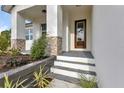 Inviting front porch with a modern glass door, stone accents, and new landscaping at 2436 Jacobs St, Port Charlotte, FL 33953