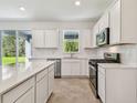 Bright kitchen with white cabinets, stainless appliances and a view of the backyard at 36424 Sespe Creek Ct, Zephyrhills, FL 33540