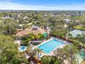 Community pool, jacuzzi, and amenities, surrounded by palm trees, a clubhouse, and tennis courts at 1007 Lake Avoca Dr, Tarpon Springs, FL 34689