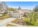 Well-manicured home with an attached garage and inviting front yard landscaping with palm trees at 1007 Lake Avoca Dr, Tarpon Springs, FL 34689