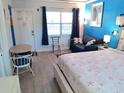 Cozy bedroom featuring bright blue walls, wood-look floors, and starfish-themed bedding at 16333 Gulf Blvd # 105, St Petersburg, FL 33708