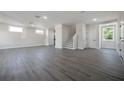 Spacious living room with gray wood-look flooring, white walls, and stairway at 3801 Luma Dr, Holiday, FL 34691