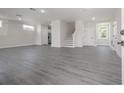 Large living room area with sleek gray laminate flooring, recessed lighting, and access to the staircase at 3801 Luma Dr, Holiday, FL 34691