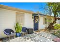 Inviting front door with awning, surrounded by a landscaped yard and relaxing blue chairs at 6104 S Main Ave, Tampa, FL 33611