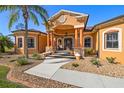 Elegant home entrance featuring a covered porch, stately columns, decorative stone accents, and meticulously maintained landscaping at 14739 Vista View Ct, Dade City, FL 33523