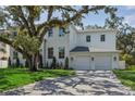 Side view of a white two-story home showcasing its well-manicured lawn and three-car garage at 4614 W Tennyson Ave, Tampa, FL 33629
