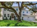 Stately two-story white home featuring a well-manicured lawn and three-car garage at 4614 W Tennyson Ave, Tampa, FL 33629