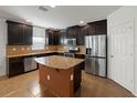 Modern kitchen boasts dark cabinets, granite countertops, stainless steel appliances, and a center island at 4734 Chatterton Way, Riverview, FL 33578