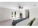 Bright main bedroom with a ceiling fan, double doors to a private balcony, and a comfortable bed at 8150 Southern Pines Dr, Brooksville, FL 34601