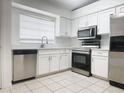 Bright kitchen with white cabinetry, stainless steel appliances, and tile flooring at 1009 Hardwood Dr, Valrico, FL 33596