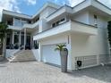 Stunning modern home featuring clean lines, a two-car garage, and lush tropical landscaping at 1522 Gulf Blvd, Indian Rocks Beach, FL 33785