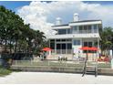 Beautiful waterfront home with multiple balconies, palm trees, and lounge area on the beach at 1522 Gulf Blvd, Indian Rocks Beach, FL 33785