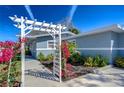 Exterior view of a charming home with an arbor covered in vibrant flowers and blue paint at 245 58Th N St, St Petersburg, FL 33710