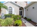 Inviting front entrance with landscaped garden, decorative bench, and arched doorway at 27045 Firebush Dr, Wesley Chapel, FL 33544
